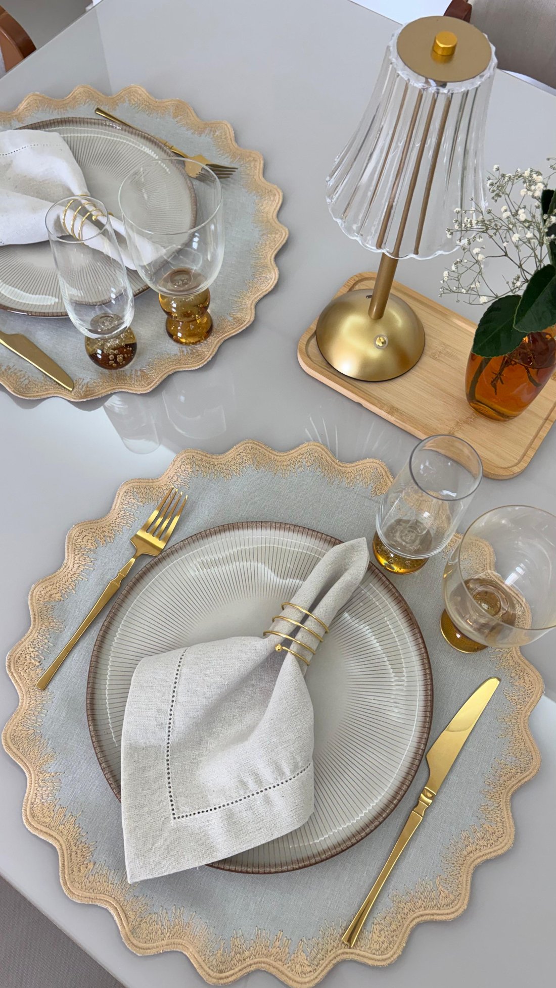 Mesa posta com lugar americano bordado, guardanapo de linho e porta-guardanapo dourado